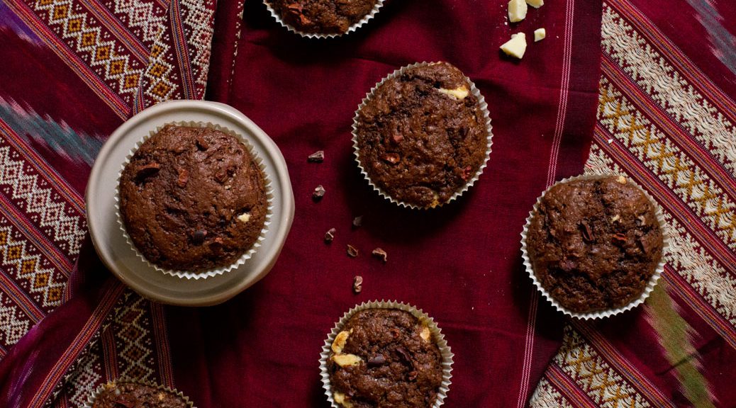 fünf Muffins auf dunkelrot gemusterter Tischdecke, vogelperspektive