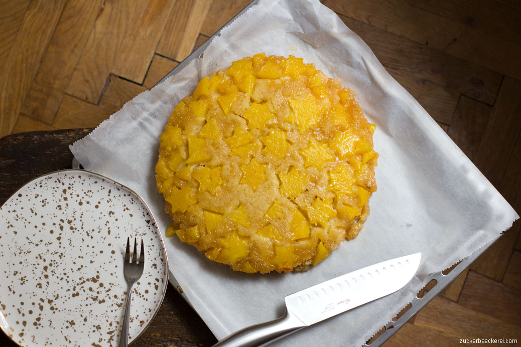 ananas tarte tatin von oben neben einem goldgesprenkelten teller und einem messer