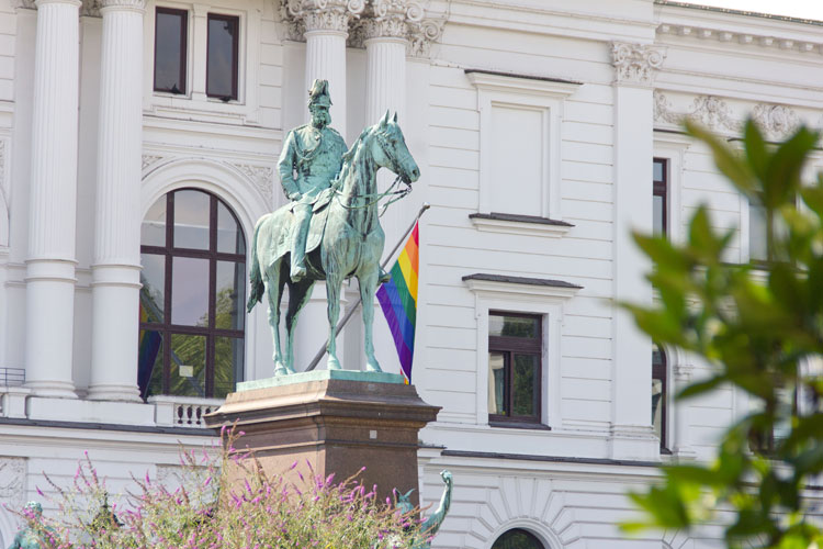 Reiterstatue Vorm Altonaer Rathaus, daran eine Regenbogenflagge