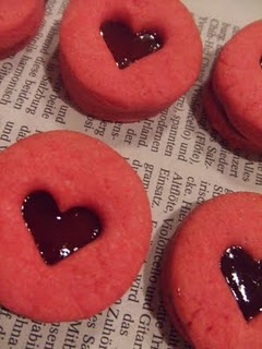 Rote Mürbteigkreise mit ausgestochenem Herz, gefüllt mit roter Marmelade