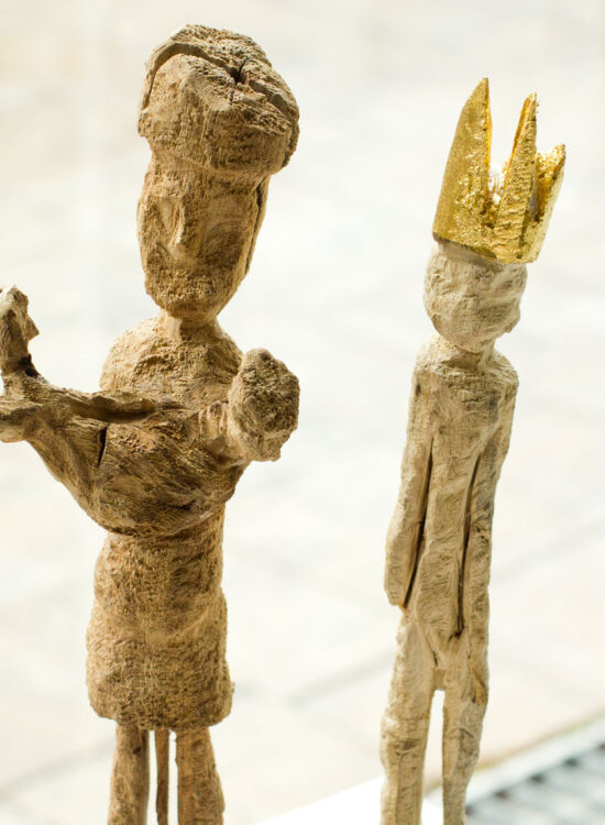 zwei geschnitzte Holzfiguren, die linke hält ein kind in den Armen, die rechte hat eine goldene Zackenkrone