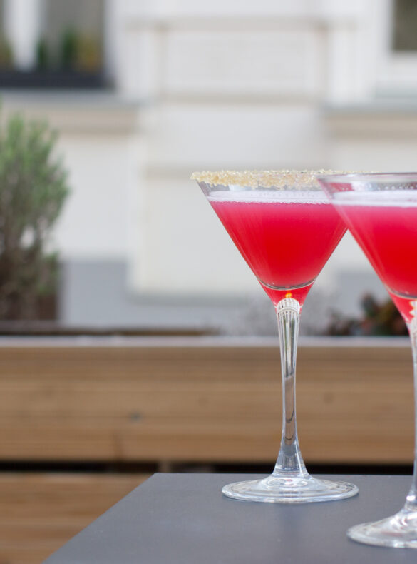 zwei Cocktailschalen mit pinken Drinks, im Hintergrund Pflanzen - Zuckersüß 426