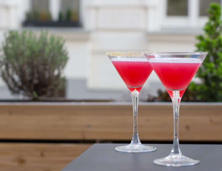 zwei Cocktailschalen mit pinken Drinks, im Hintergrund Pflanzen - Zuckersüß 426