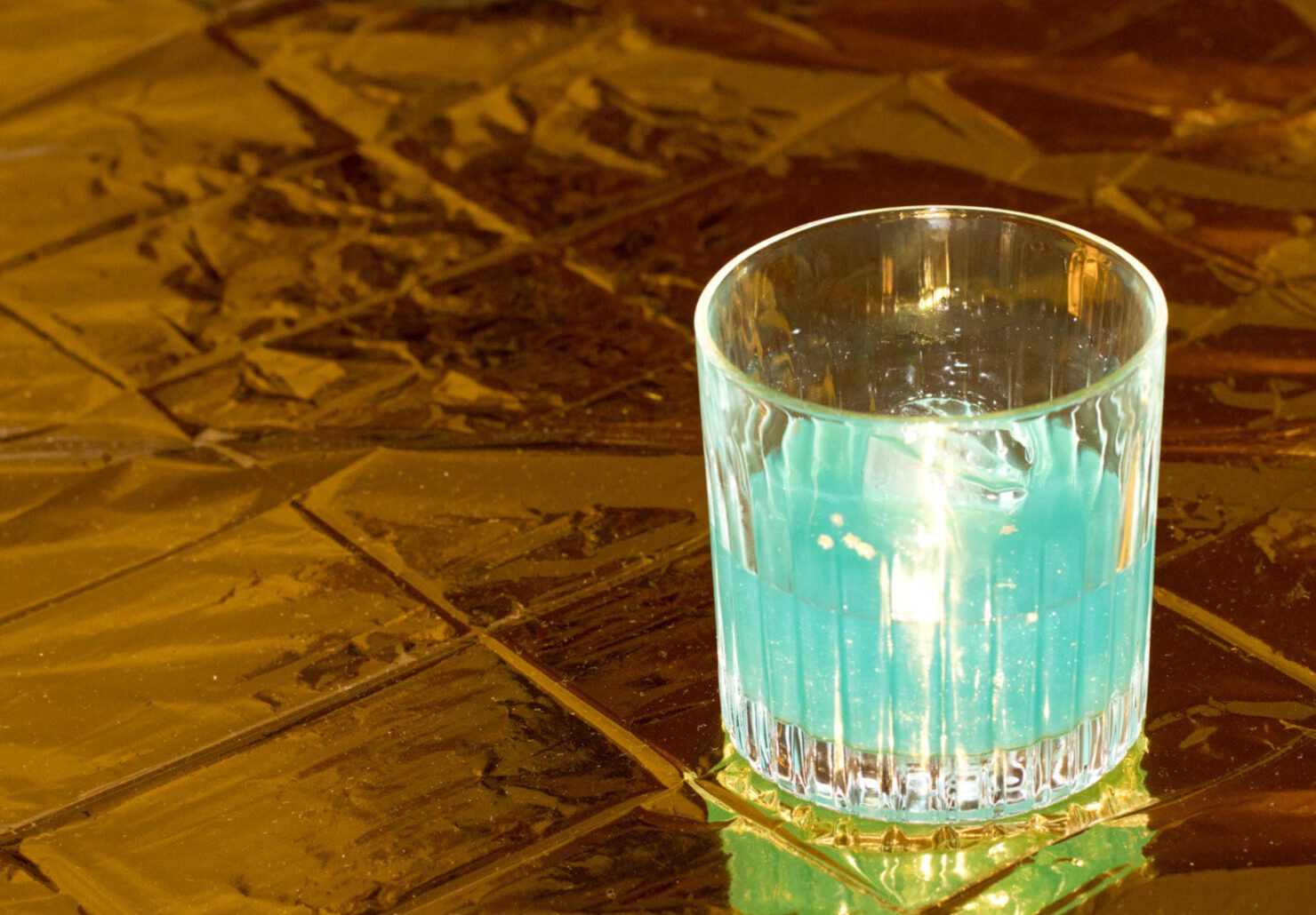 blauer cocktail auf goldener oberfläche