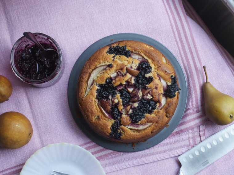 Runder Kuchen, auf der Oberfläche dunkle eingebackene Kleckse aus Apfel-Hollerröster und Birnenstückchen